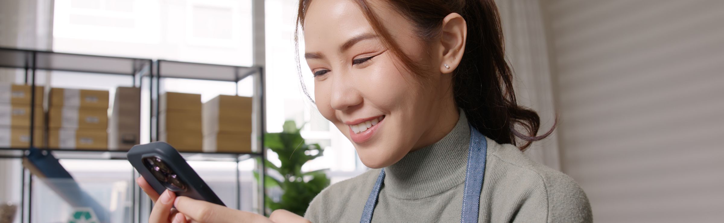 Store clerk in apron looking at phone interacting with a chatbot