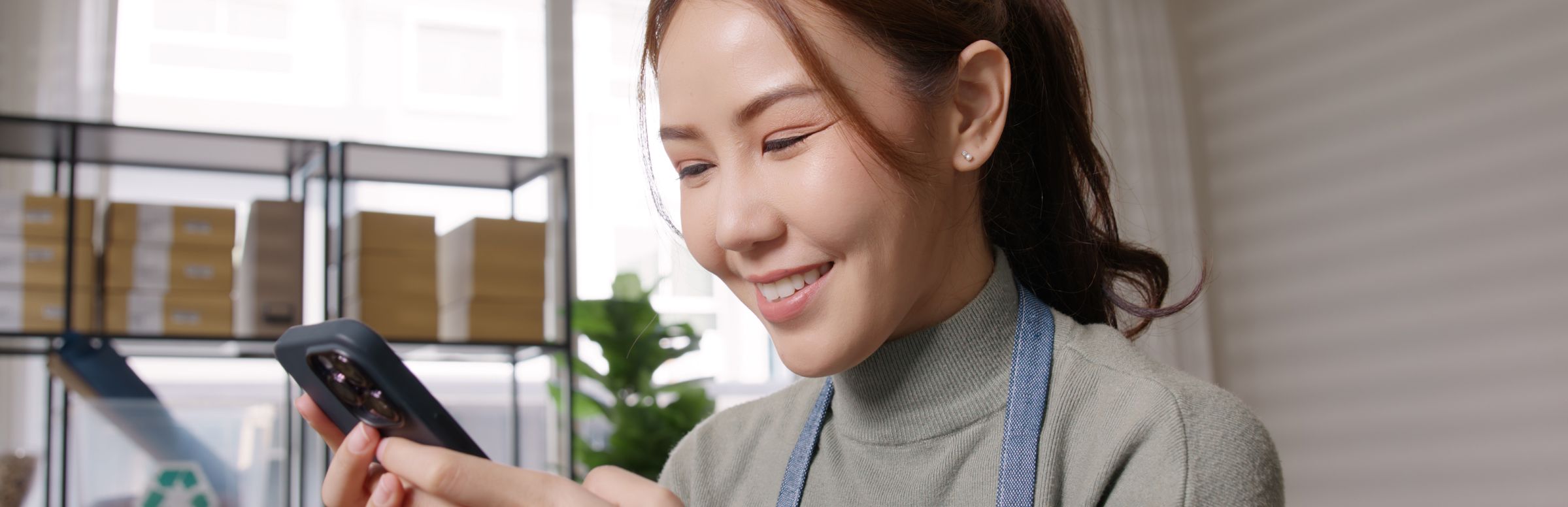 Store clerk in apron looking at phone interacting with a chatbot