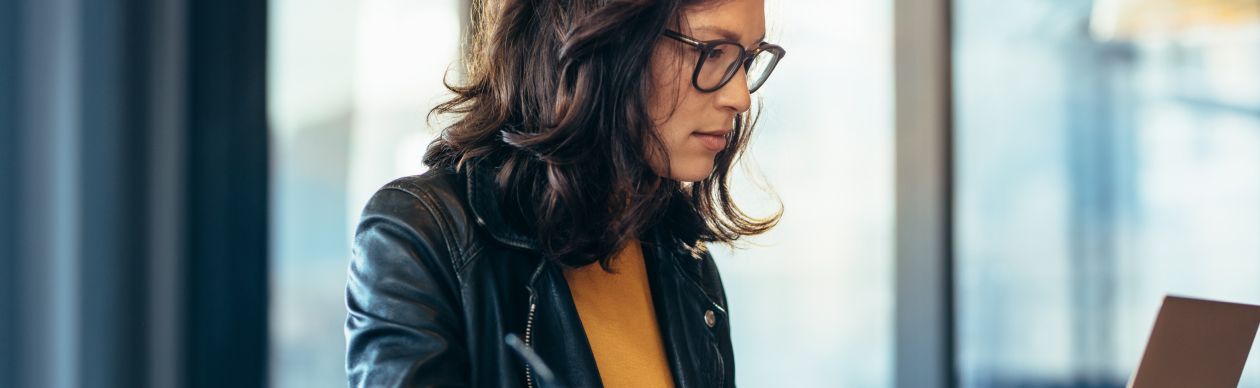 A bespectacled businesswoman looking at a laptop