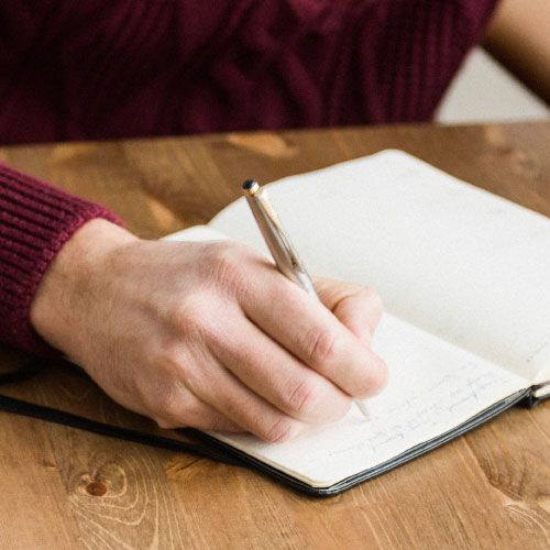 Hand holding pen writing in notebook