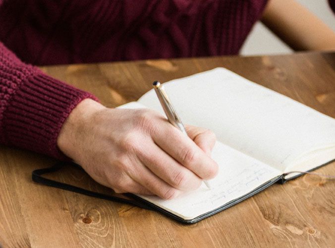 Hand holding pen writing in notebook
