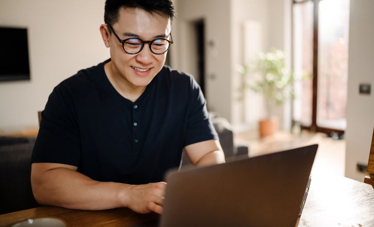 Bespectacled man working on a laptop