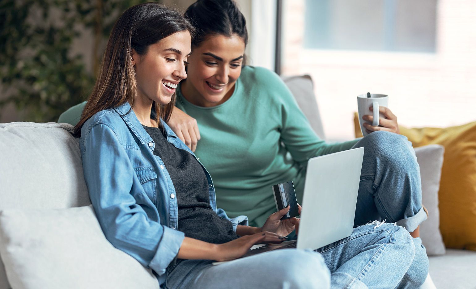 Two women shopping on a laptop
