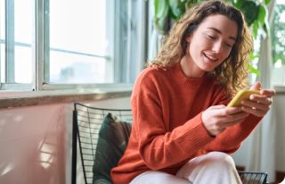 Seated woman smiling at her yellow smartphone