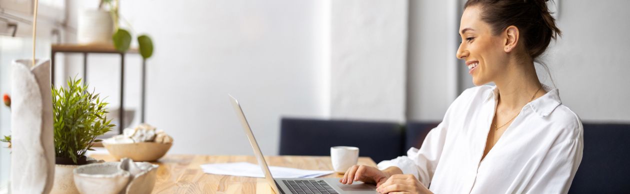Woman in a white shirt looking at a laptop on a desk