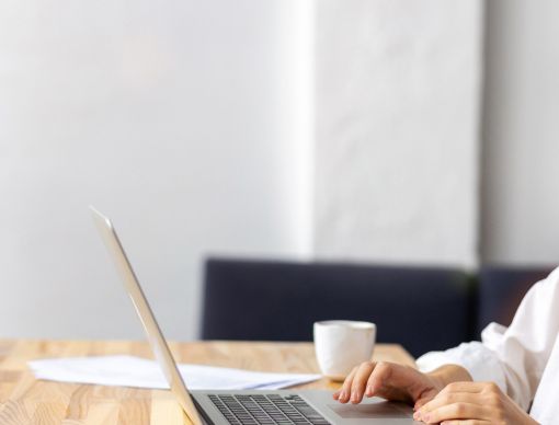 Woman in a white shirt looking at a laptop on a desk