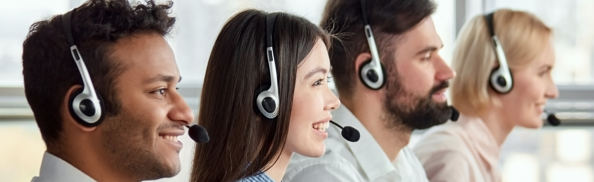 Four customer support agents wearing head sets, sitting in a row