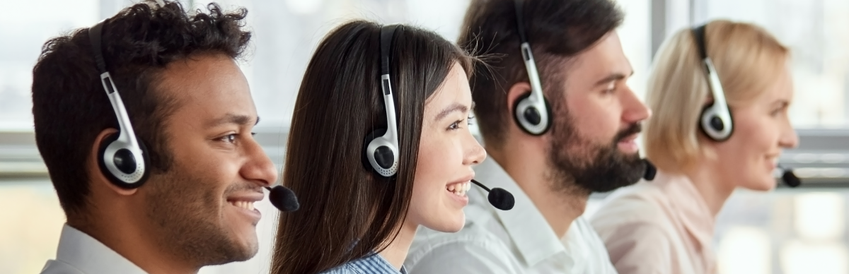Four customer support agents wearing head sets, sitting in a row