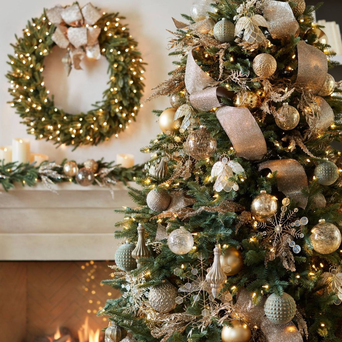 Festive Christmas scene with a decorated tree featuring gold ornaments and ribbons. A lit wreath and candles adorn the mantel, creating a warm, cozy atmosphere.