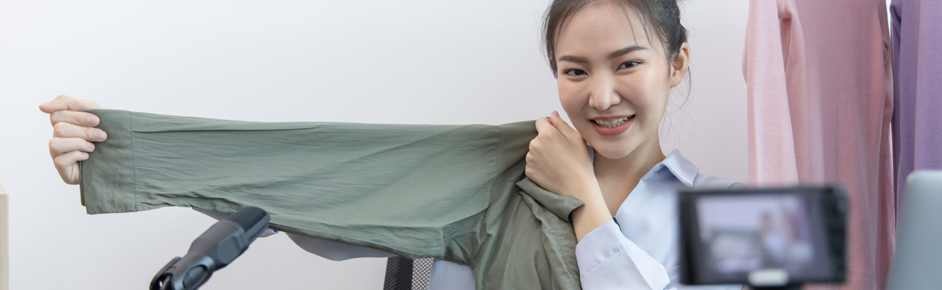 Woman filming herself on her phone holding up a green shirt