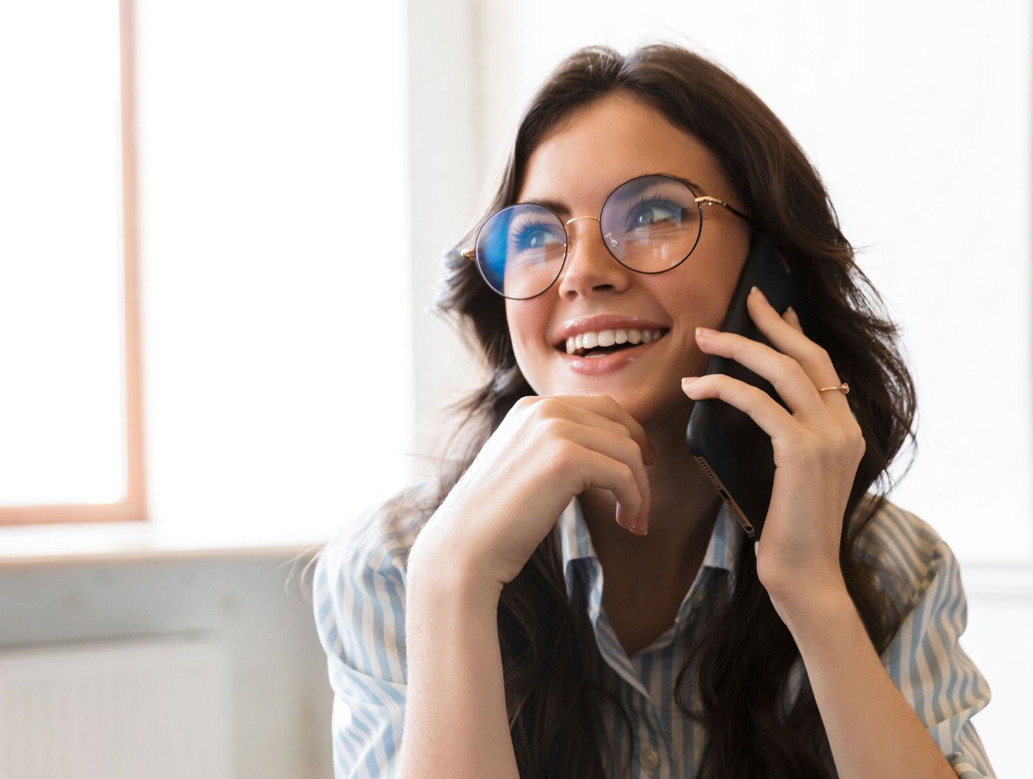 Woman with glasses smiling off into space while on phone