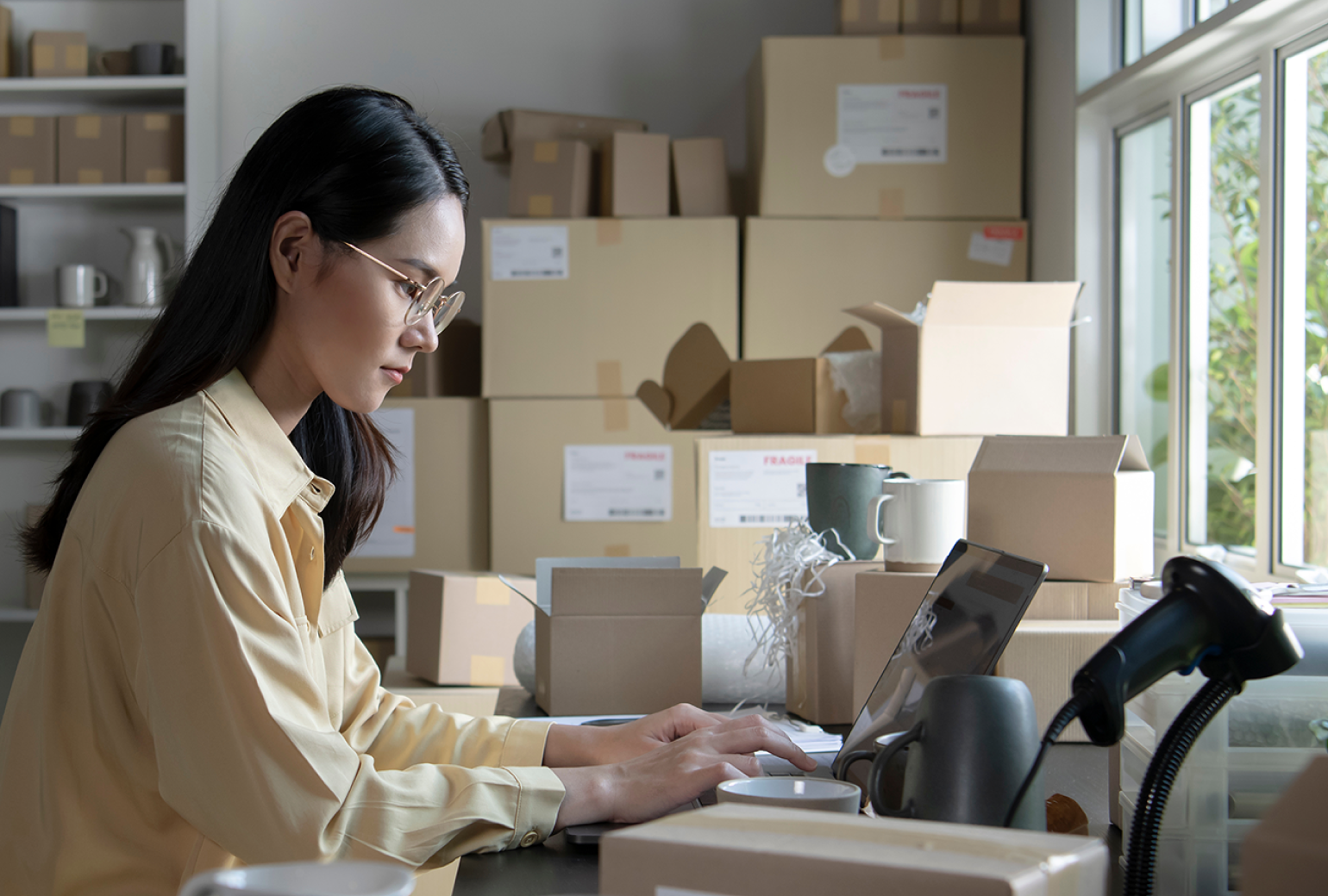 Woman on a laptop in a room full of boxes