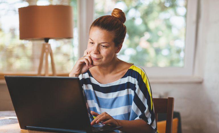 woman looking thoughtfully at laptop