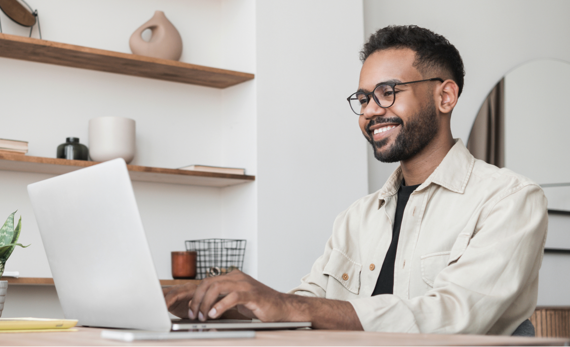 Man in glasses sitting at his desk and typing on his laptop