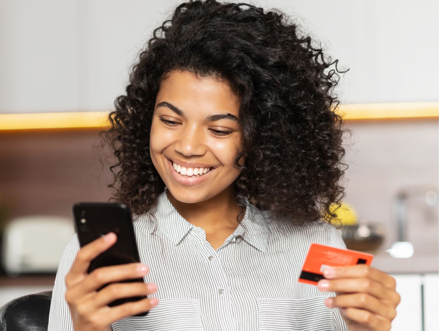 Woman smiling at phone while purchasing something with credit card