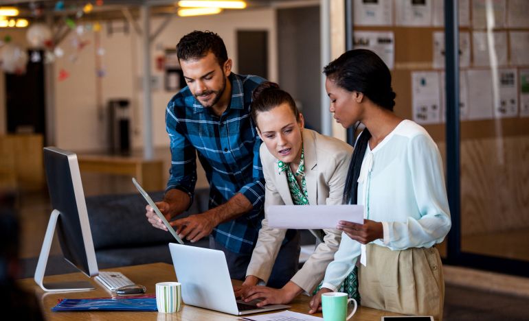 A group of CX leaders huddling over a computer to compare Salesforce service cloud with Gladly