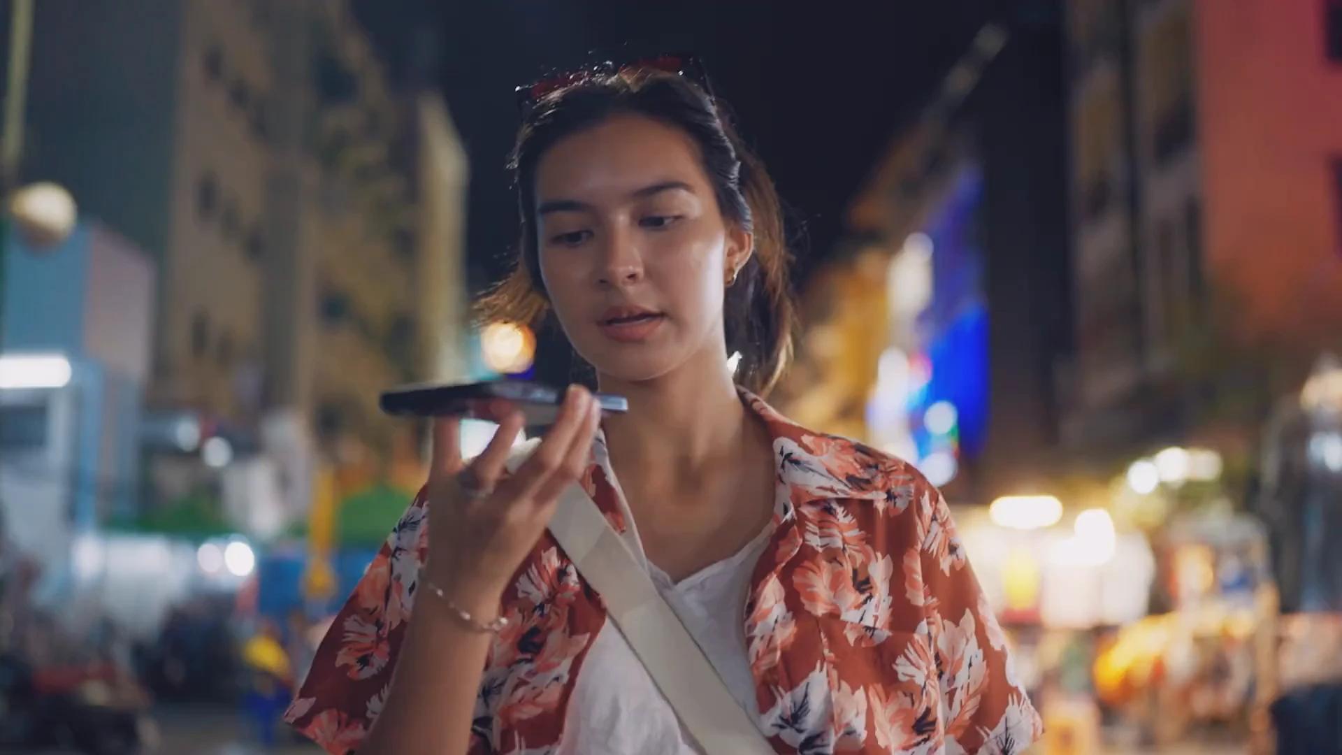 Woman speaking into her phone on a busy night-market street