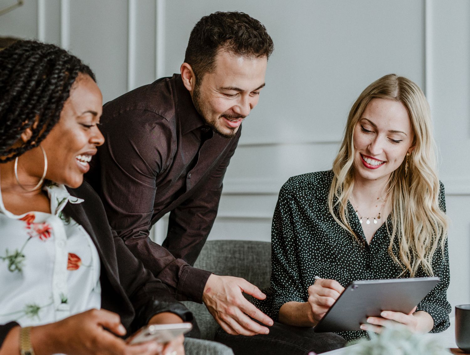 Two people gathered over a woman pointing something out on her ipad
