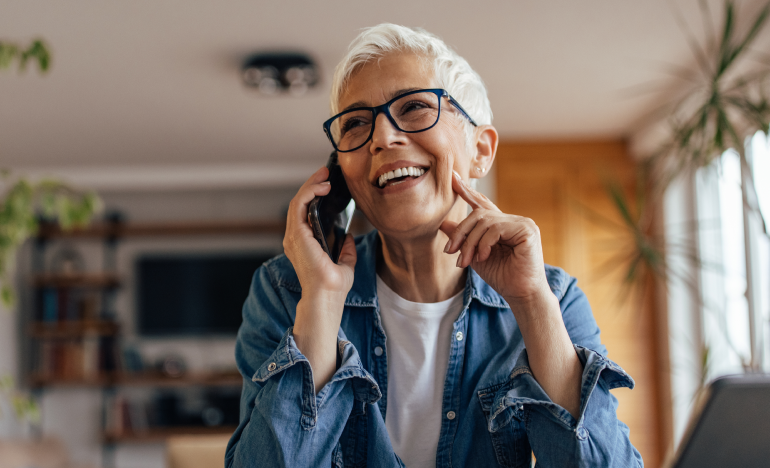Older woman with glasses smiling and talking on her smartphone