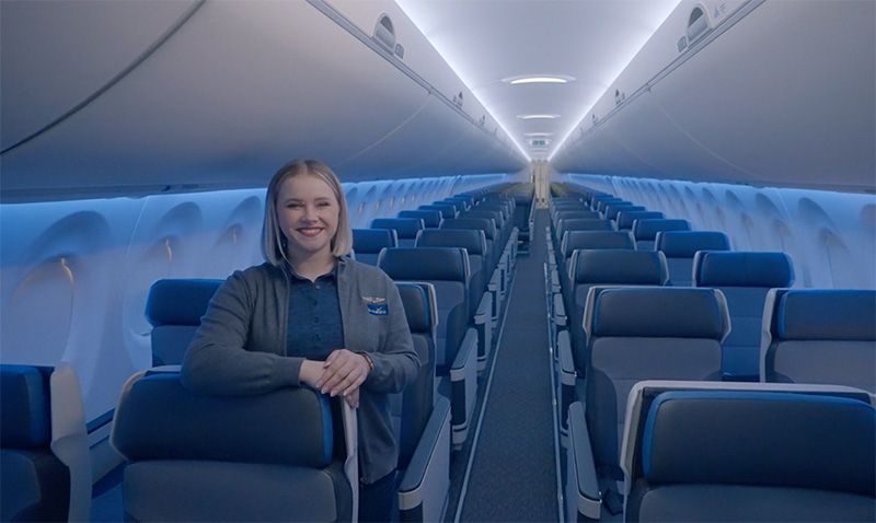 A Breeze Airways flight attendant standing on a plane