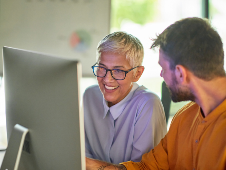 Woman and man smiling at computer in office