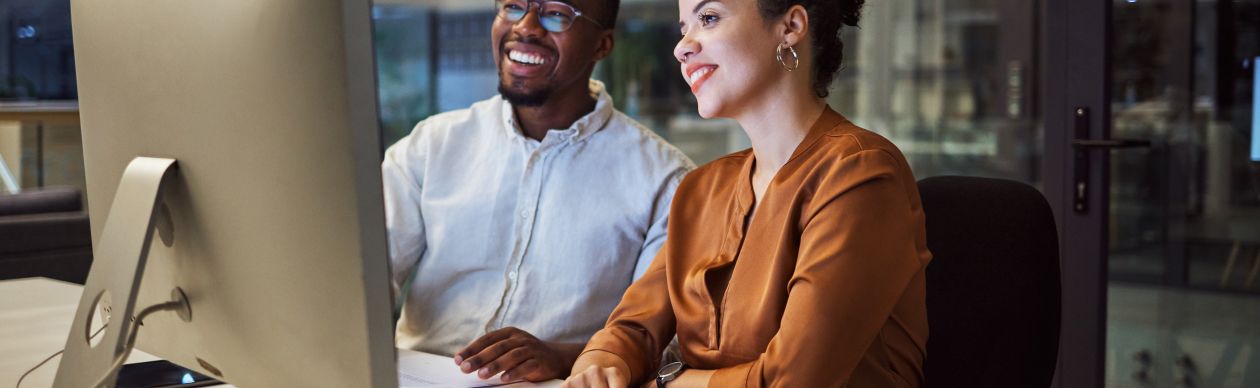 Two coworkers chatting together and looking at a computer monitor