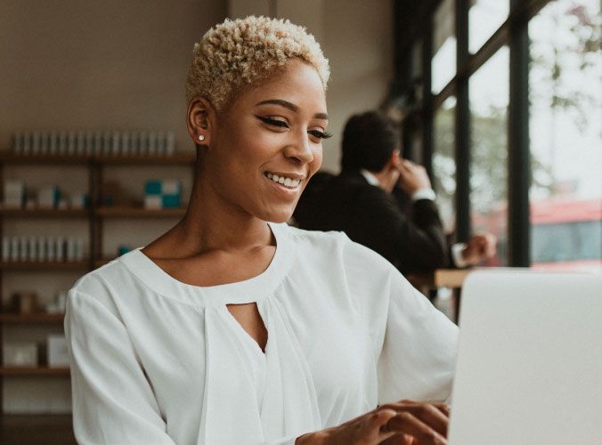 Woman smiling at laptop in a coffee shop