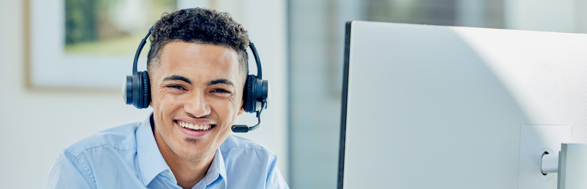 Man wearing headset in front of desktop computer