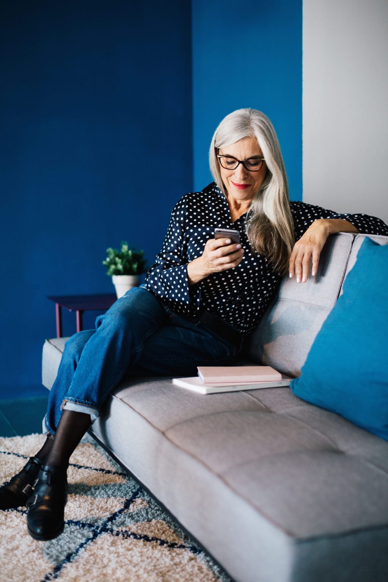 Portrait Of A Senior Businesswoman Sitting On Sofa Using Her Phone.