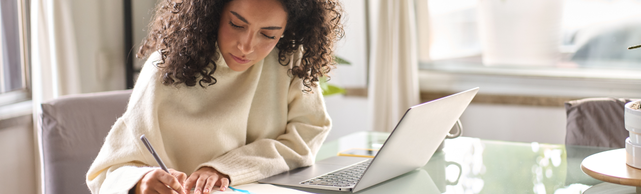 woman writing notes while using her laptop and tablet