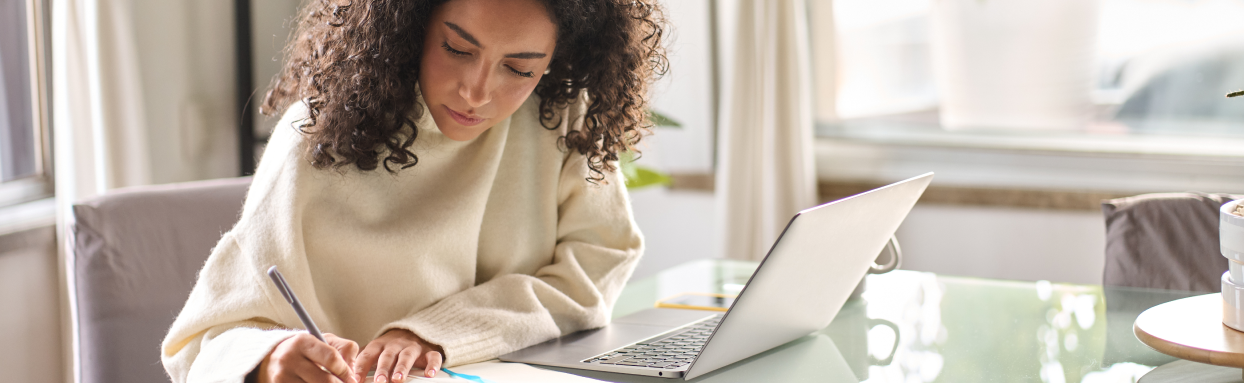woman writing notes while using her laptop and tablet