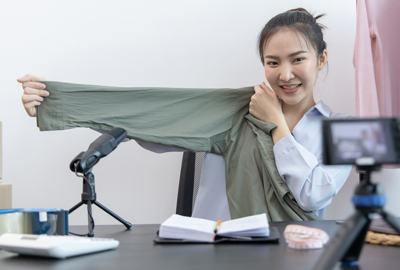 Woman filming herself on her phone holding up a green shirt