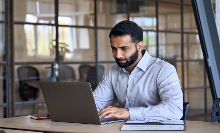 Bearded businessman staring seriously at a laptop