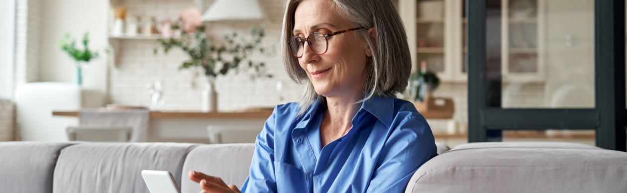 Older woman sitting on her living room couch and working on a tablet