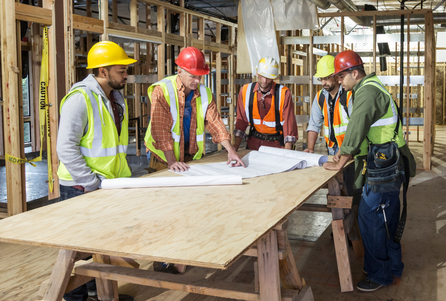 Construction workers talking around blueprints