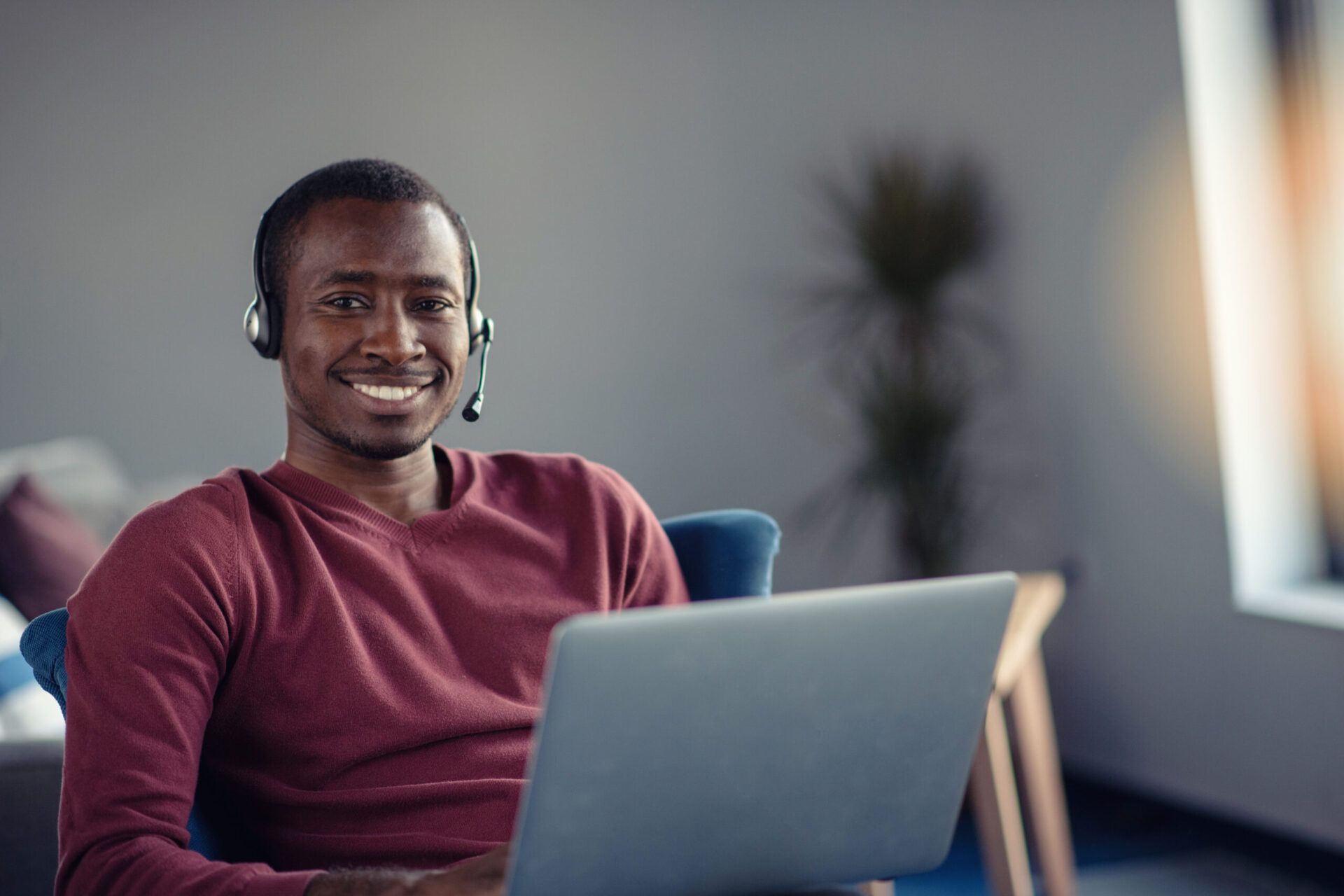 Man wearing headset on laptop smiling at camera