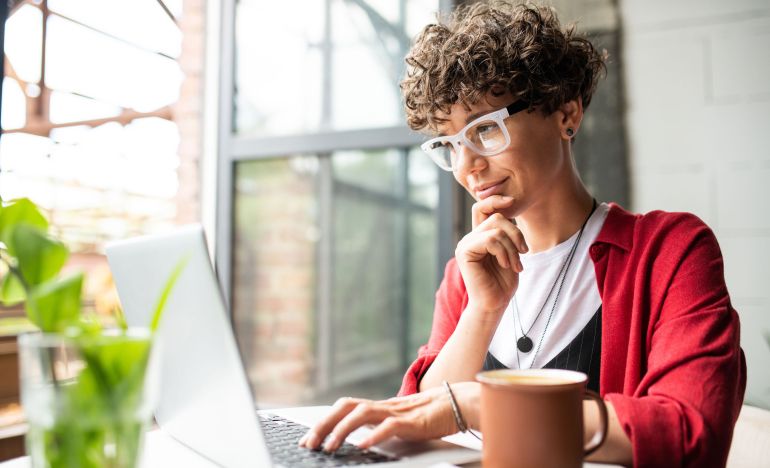 Bespectacled woman looking ponderously at her laptop