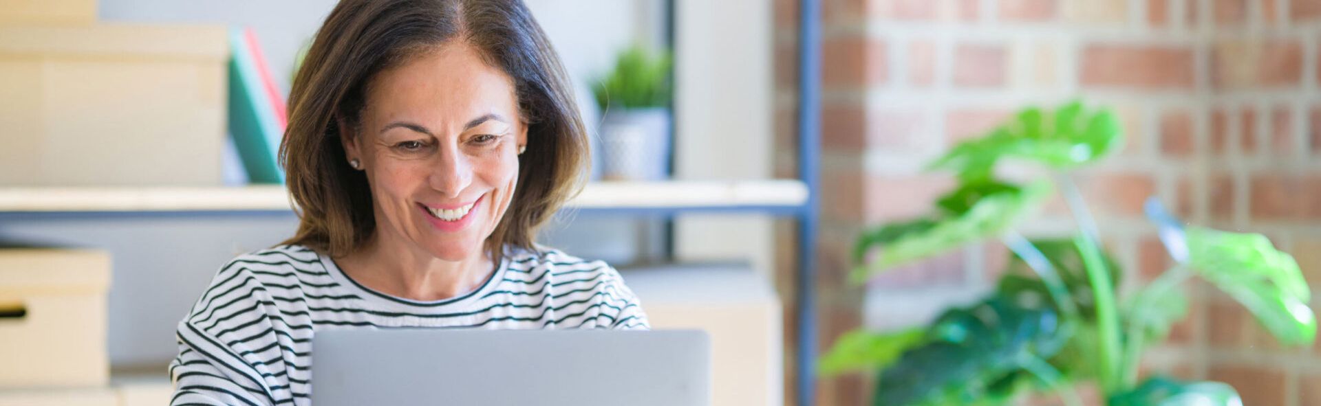 Woman in a striped shirt smiling at a laptop