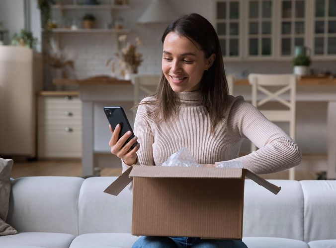 Customer unboxing a package and looking at her phone