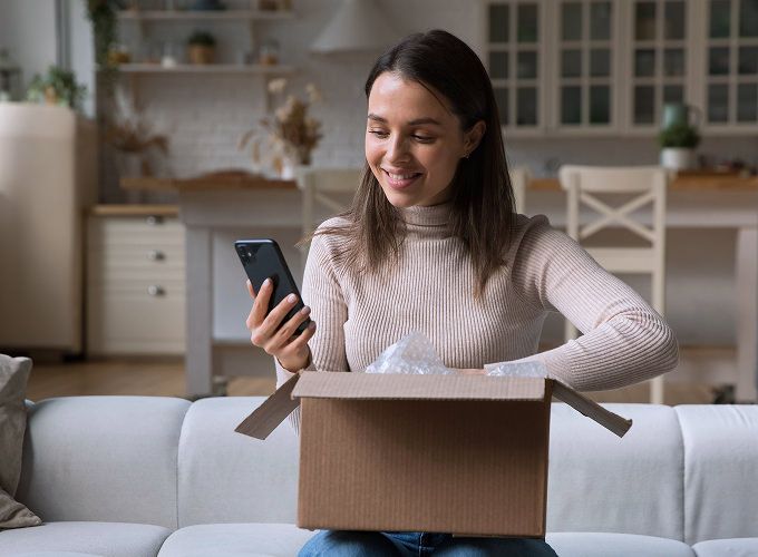 Customer unboxing a package and looking at her phone