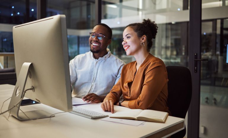 Two coworkers chatting together and looking at a computer monitor