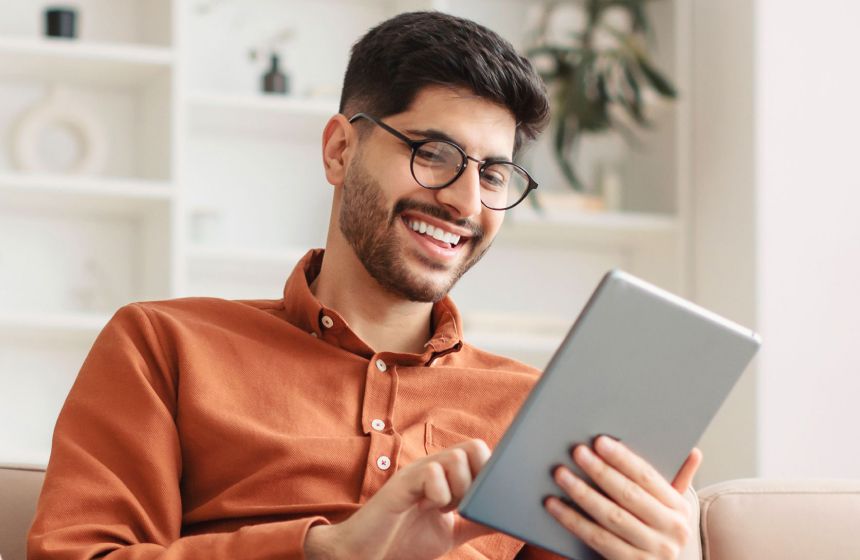 Man with glasses smiling at ipad