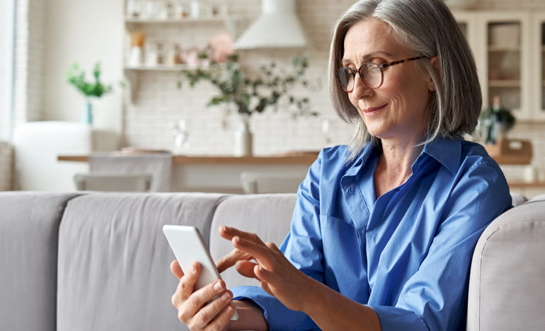 Older woman sitting on her living room couch and working on a tablet