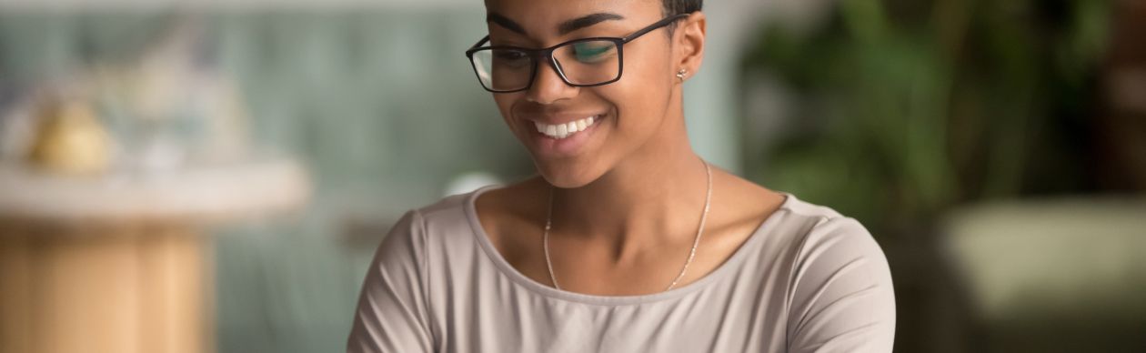 Bespectacled woman smiling down at her laptop