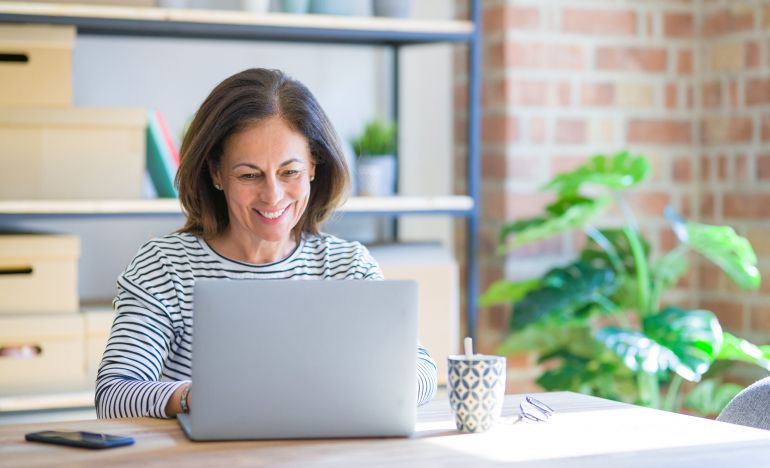 Woman in a striped shirt smiling at a laptop