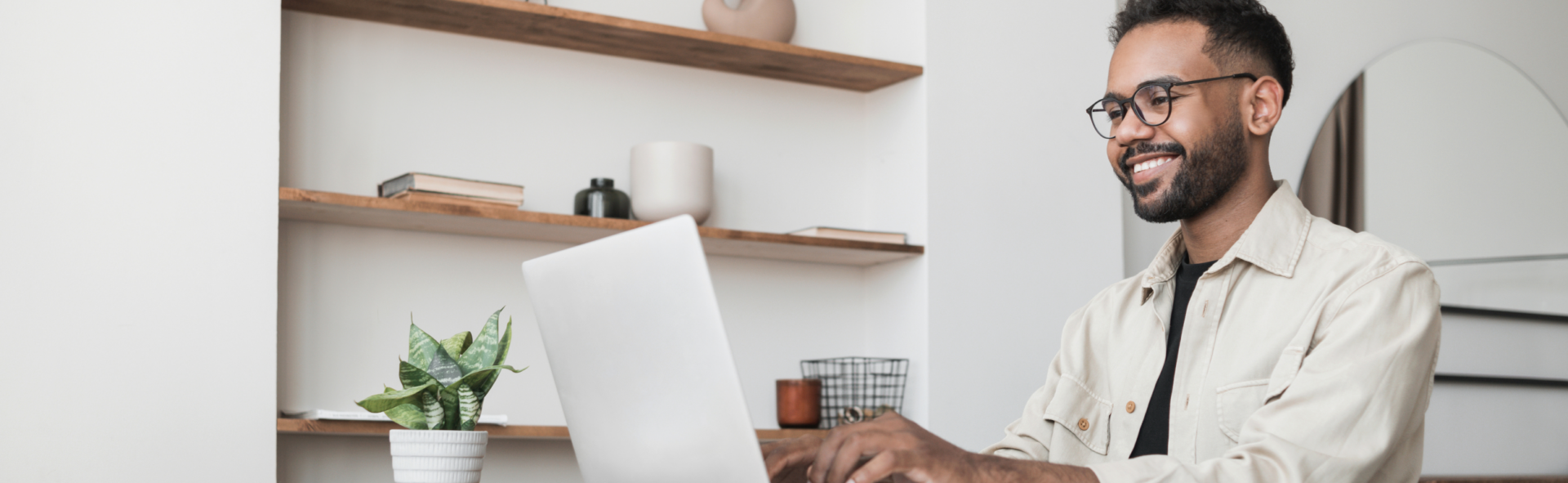 Man in glasses sitting at his desk and typing on his laptop
