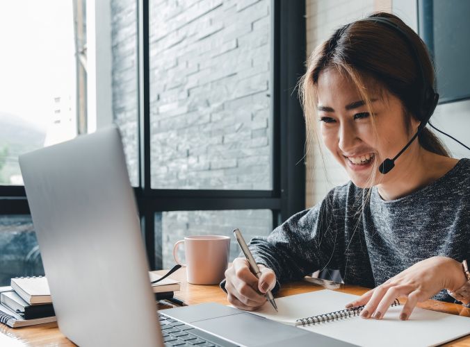Customer support agent wearing headset while using her laptop