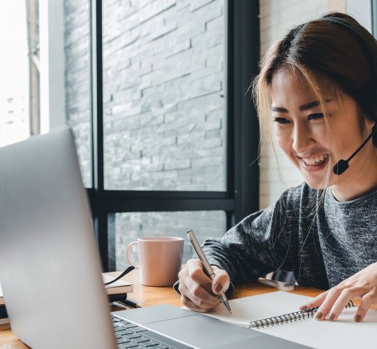 Woman with a headset smiling at her computer