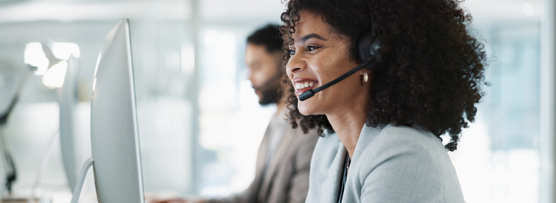 Customer support agent smiling at computer in office