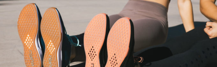 Two people sitting with their feet out wearing KURU shoes